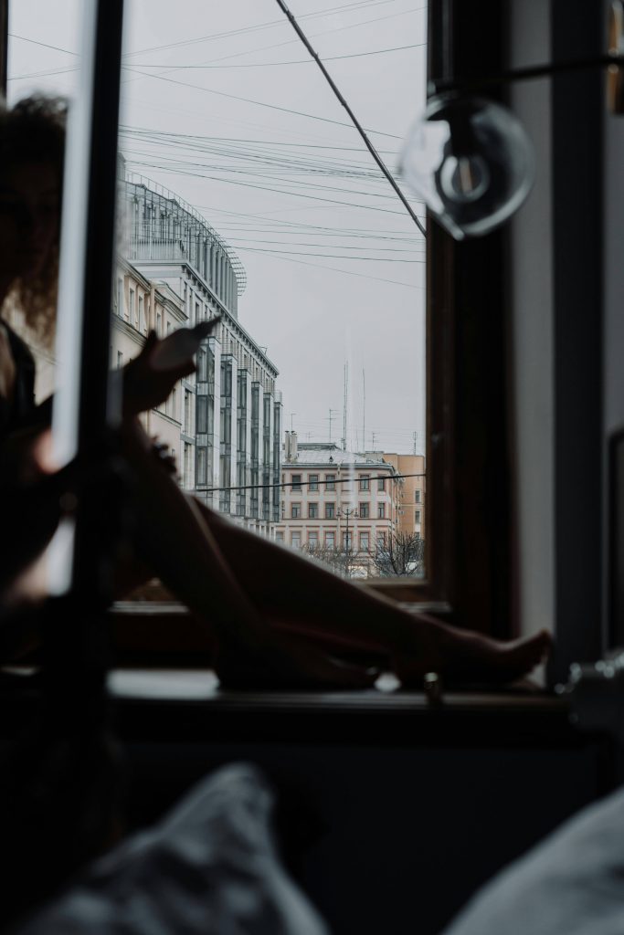 Person, die am Fenster sitzt in dunkler Kulisse.