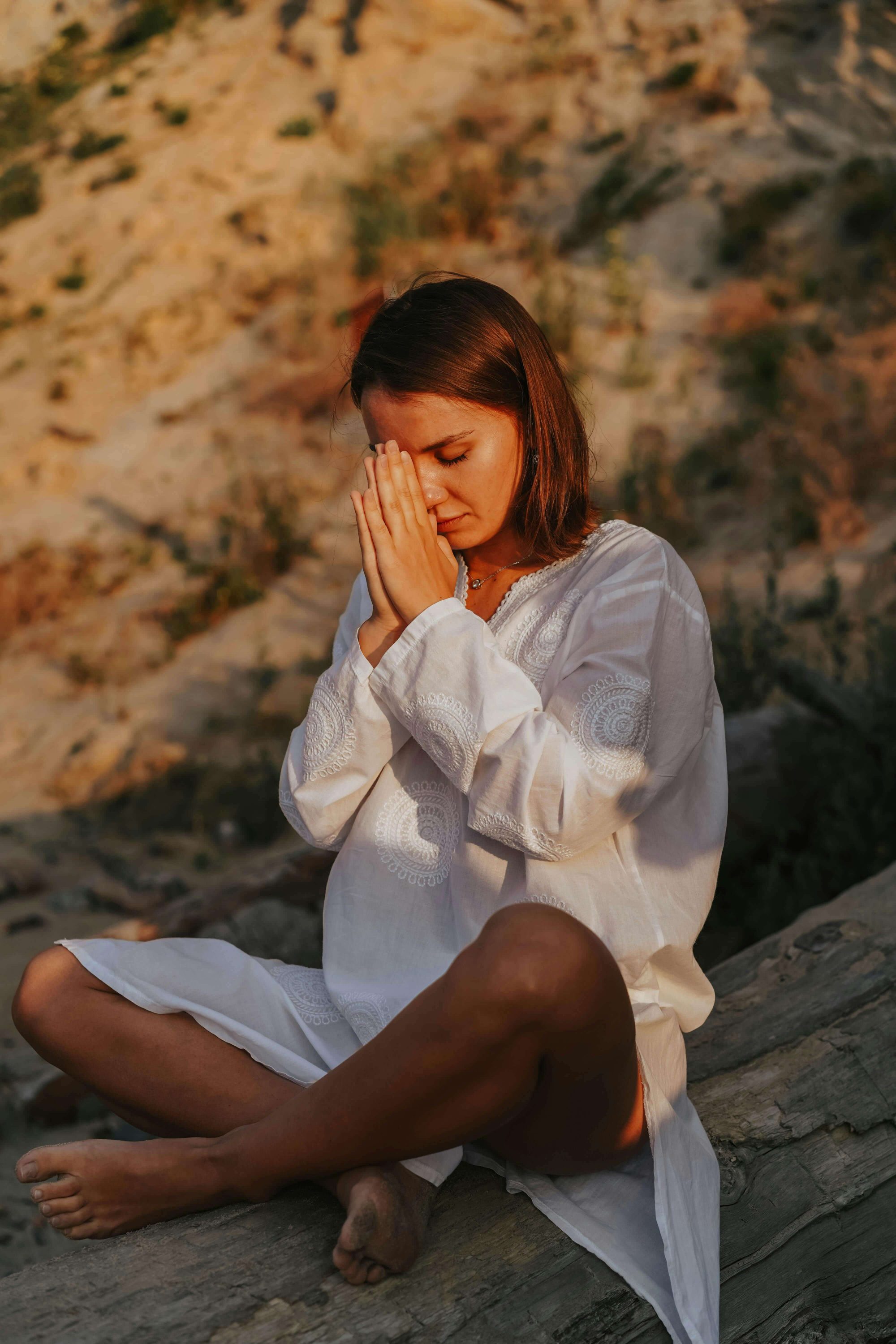 Frau, die im Schneidersitz sitzt und die Hände in Gebetshaltung vor ihr Gesicht hält. Symbolisch für Ruhepausen, die hochsensitive Menschen sich nehmen.