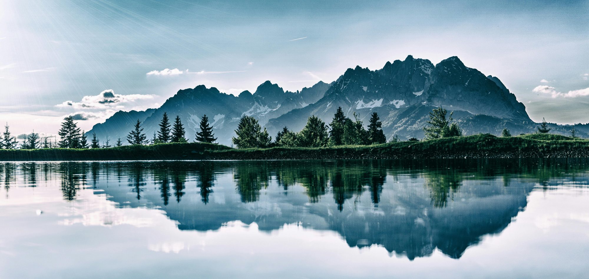 Ruhiger Bergsee mit Spiegelung der Berge in natürlicher Landschaft