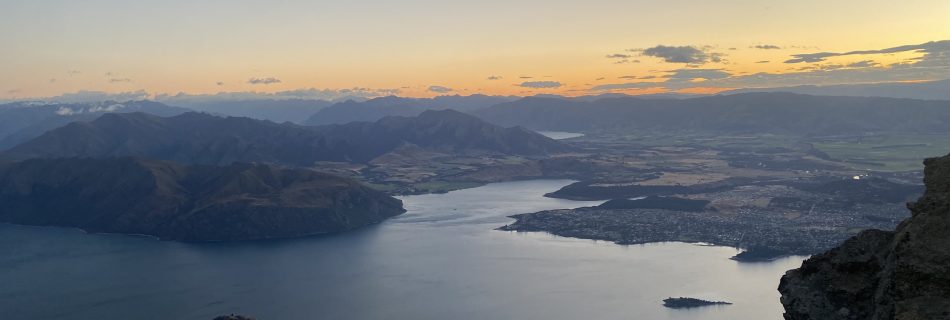 Sonnenaufgang am Roy’s Peak mit Blick über den Lake Wānaka und die umliegenden Berge in Neuseeland.